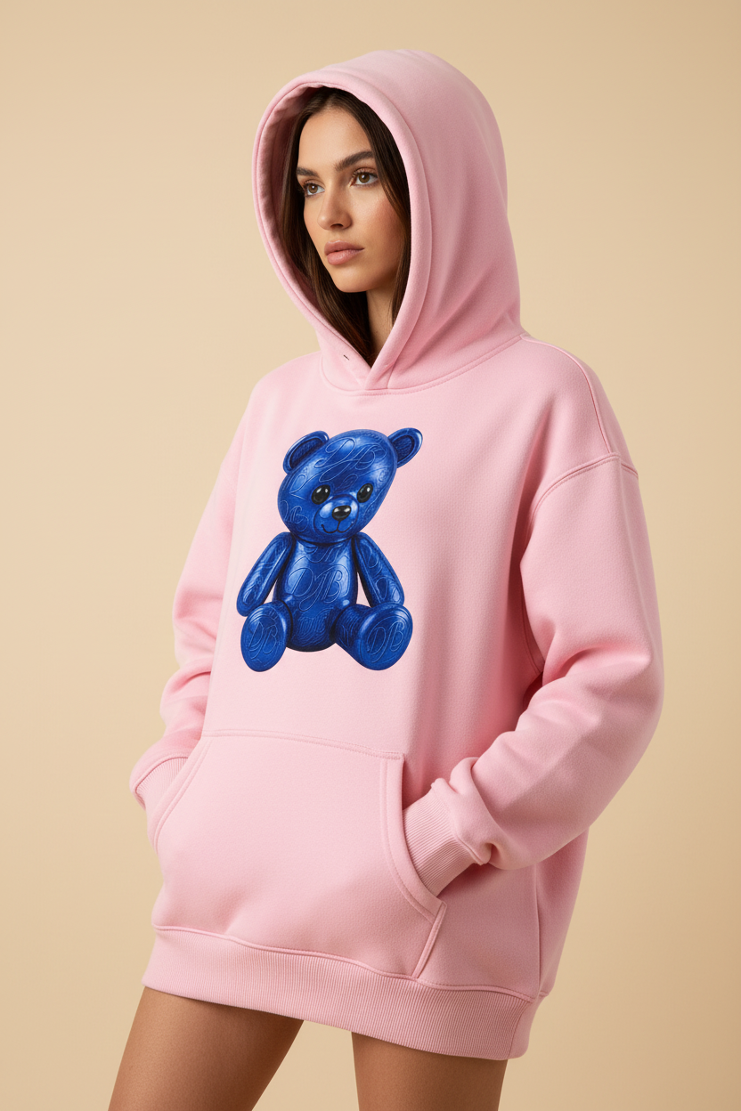 Close-up of the pink Teddy Oversize Fleeced Hoodie showing the fleece, hood, ribbing, pocket, stitching, and blue teddy artwork