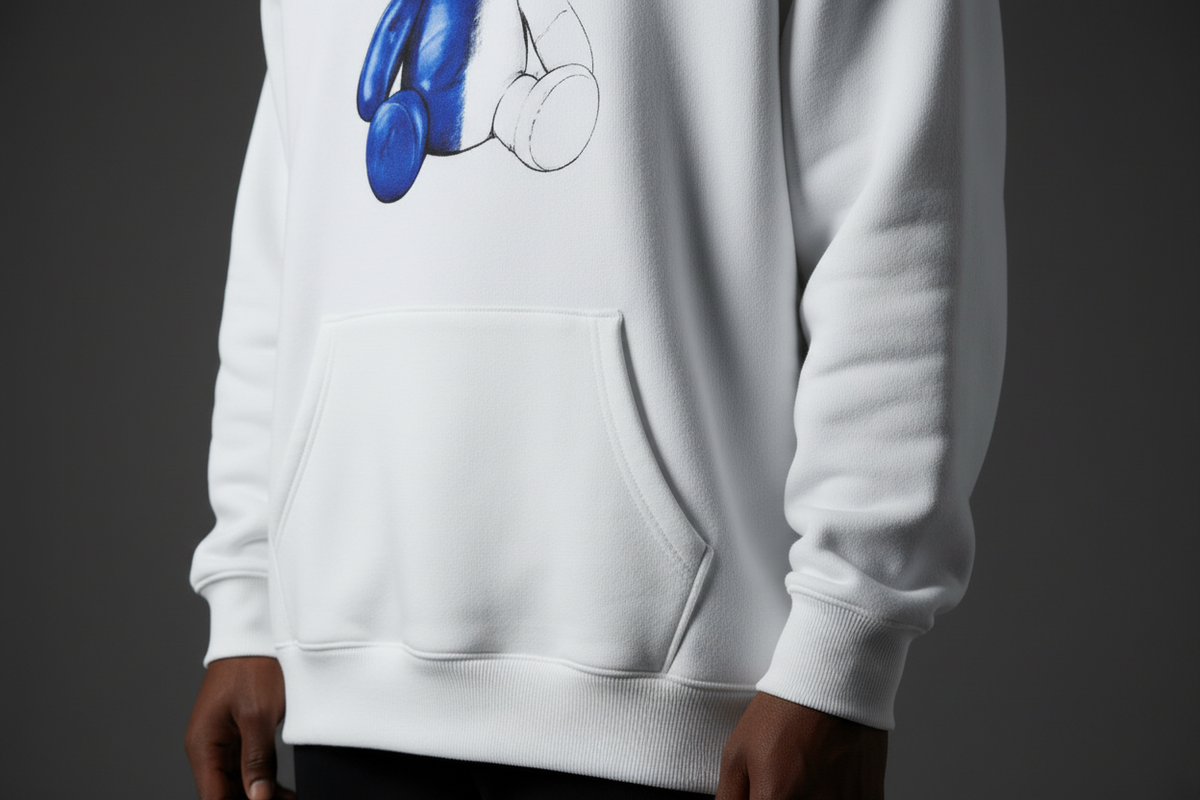 Close-up of the WIP Hoodie showing heavyweight fleece thickness, ribbed cuffs, stitching, and teddy bear chest print